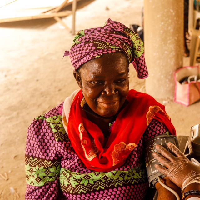 Close-up of a carer's hands gently holding an older woman's hands in a moment of support.