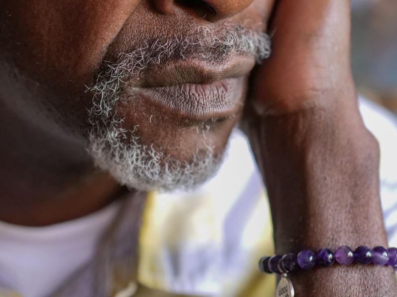 Close-up of an older man&rsquo;s thoughtful face, resting his hand against his cheek.